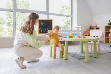 Evde annesinin sandalyesinden inen tatlı bir kız bebek.