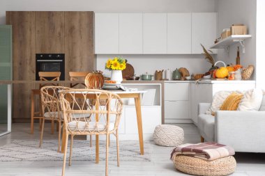 Tabaklar balkabağı şeklinde, böğürtlen ve sonbahar çiçekleri açık mutfakta masada.