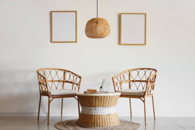 Hasır lambalı, koltuklu ve boş çerçeveli oturma odasının içi.