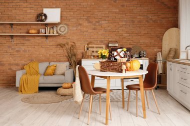 Mutfağın içinde sonbahar dekorasyonu, yemek masası ve kanepe var.