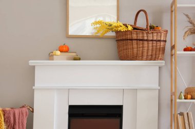 Çiçekli sepet ve şöminenin üzerinde balkabağı.