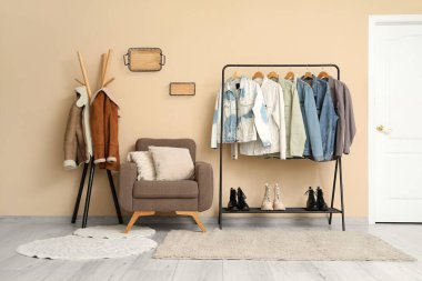 Soyunma odasının iç tarafında sonbahar kıyafetleri, askılar ve koltuklar var.