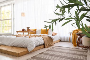 Yatak ve penceresinde kahvaltı olan aydınlık yatak odasının içi