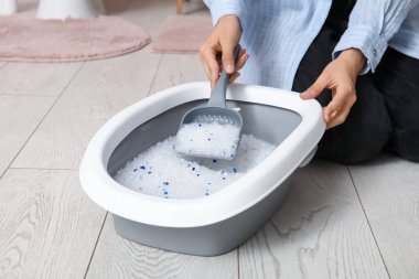 Tuvaletteki kedi için kepçe kepçesi temizleyen kadın.