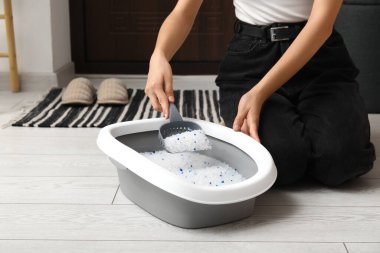 Koridordaki kedi için kepçe kepçesi temizleyen kadın.