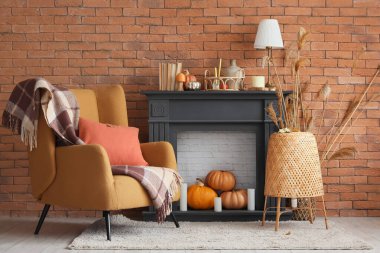 Şömine, yumuşak koltuk, ekose, lamba ve balkabakları sonbahar oturma odasında.