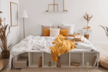 Yatak odası, raf ünitesi ve vazo dolusu otla kaplı.