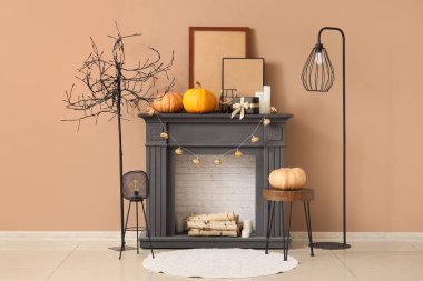 Sonbahar salonunda siyah şömine, kahve masası, lamba ve balkabağı.