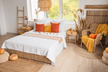 Yatak, koltuk, yastık ve balkabağı olan rahat bir yatak odası.