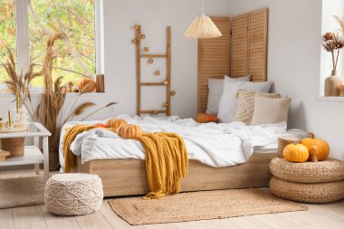 Şık bir yatak odası, rahat bir yatak, sehpa, kanepe ve balkabağı.