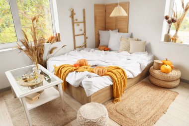 Şık bir yatak odası, rahat bir yatak, sehpa, kanepe ve balkabağı.