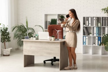 Ofisteki masasında ev modeli ve rüzgar türbiniyle cep telefonuyla konuşan kadın mühendis.