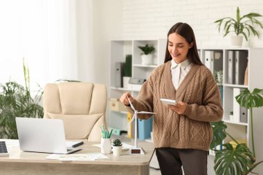 Ofisteki masasında hesap makinesi ve rüzgar türbini modeli olan kadın mühendis