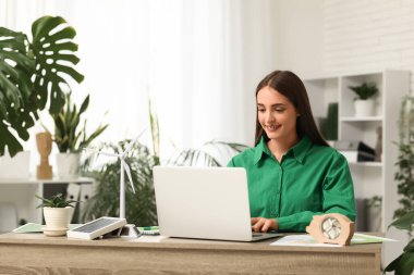 Ofisteki masada dizüstü bilgisayar ve rüzgar türbiniyle çalışan kadın mühendis.