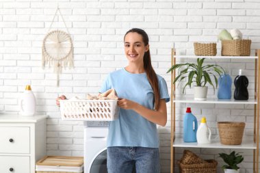 Evinde bir sepet temiz çamaşırları olan güzel, genç bir kadın.