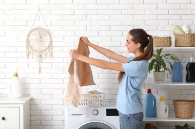 Evinde bir sepet temiz çamaşırları olan güzel, genç bir kadın.