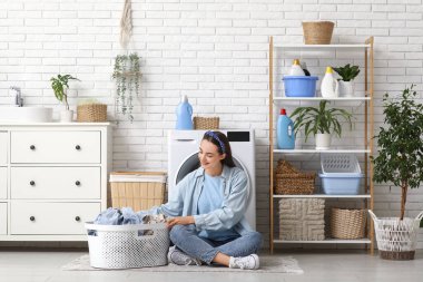 Bir sepet dolusu temiz çamaşırları olan güzel, genç bir kadın evde oturuyor.