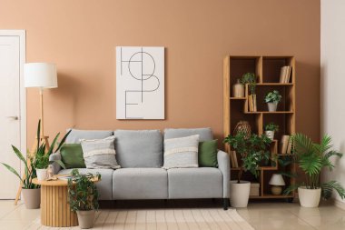 Koltuk, kahve masası, raf ünitesi ve oturma odasının iç tarafındaki bitkiler.