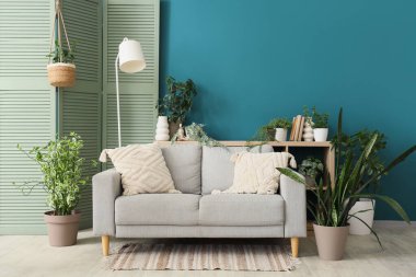 Kanepe, lamba, katlanan ekran ve oturma odasının içindeki bitkiler.