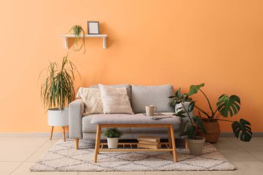 Oturma odasının iç tarafında rahat bir kanepe, bank ve çiçekler var.