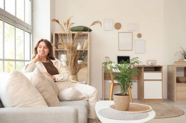 Oturma odasındaki kanepede oturan genç kadın.