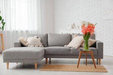 Oturma odasının içinde, masasında vazo ve gladiolus çiçekleri olan bir masa.