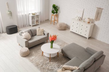 Oturma odasının içinde kanepeler ve vazoda gladiolus çiçekleri var.