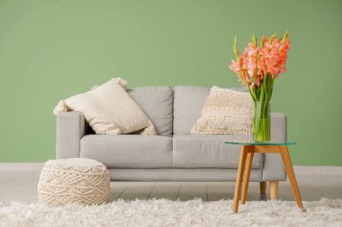 Oturma odasının içinde, masasında vazo ve gladiolus çiçekleri olan bir masa.