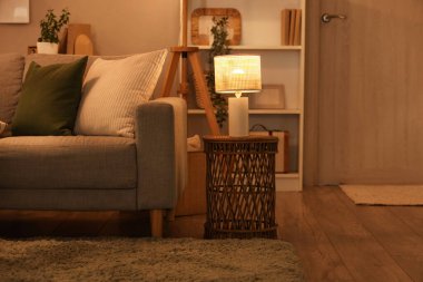 Koltuk, raf ünitesi ve oturma odasının içinde parlayan lambalar.