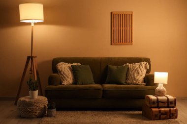 Konforlu kanepe, bavul, lamba ve pouf oturma odasının iç tarafında.