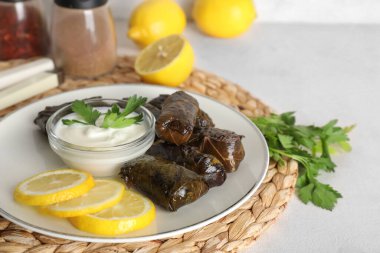 Lezzetli Dolmas tabağı (doldurulmuş üzüm yaprakları), limon dilimleri ve ışık masasında ekşi krema