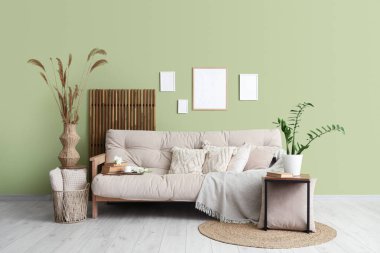 Oturma odasının iç tarafında otlu ve çiçekli rahat bir kanepe.