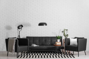 Siyah deri kanepe, sehpa, koltuk ve lambalar oturma odasında.