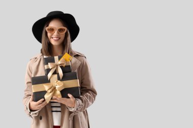 Işık arka planında hediye kutuları olan şık genç bir kadın. Kara Cuma İndirimi