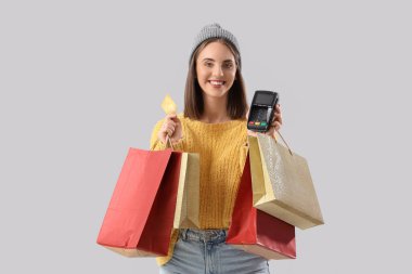 Alışveriş çantaları, kredi kartı ve ödeme terminali olan genç bir kadın. Kara Cuma İndirimi
