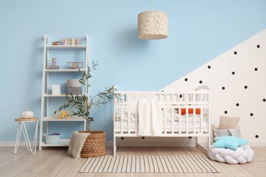 Çocukların odasının içindeki mavi duvarın yanında ekose ve raf üniteli şık beyaz bir beşik.