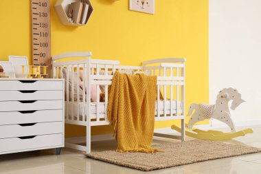 Şık çocukların yatak odasının içinde beşik, sallanan at ve stadyum ölçer var.