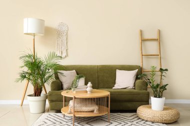 Oturma odasının içinde yeşil kanepe, lamba ve bitkiler var.