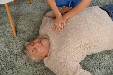 Doktor baygın yaşlı adama ilk yardım sağlıyor.