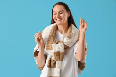 Mavi arka planda kulak tıkacı olan genç bir kadın.