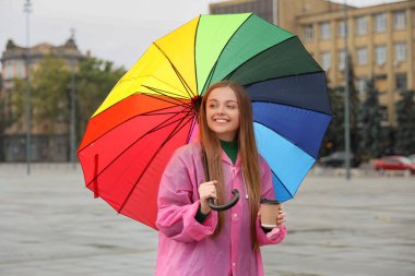 Yağmurlu bir günde yağmurluk giymiş güzel, mutlu bir kadın.