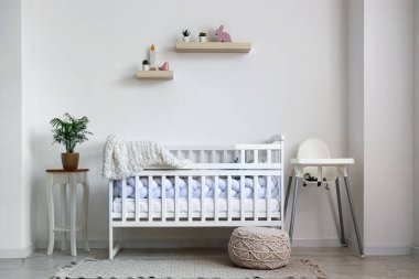 Bebek beşiği ve sandalyesi olan çocuk odasının içinde.