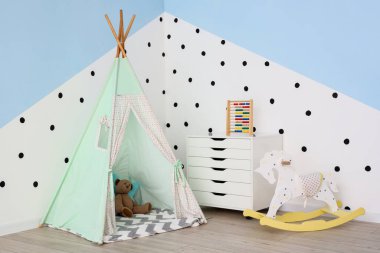 Oyun çadırı, çekmecesi ve sallanan atı olan çocuk odasının içinde.