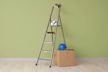 Boya malzemeli merdiven ve yeşil duvarın yanındaki kutu.