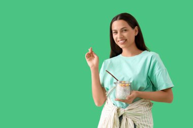 Yeşil arka planda chia tohumu pudingi olan genç bir kadın.