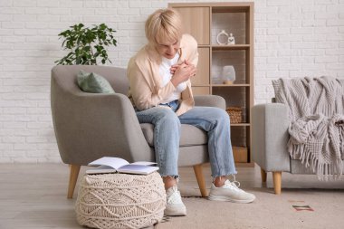 Olgun bir kadın evdeki koltukta otururken kalp krizi geçiriyor.