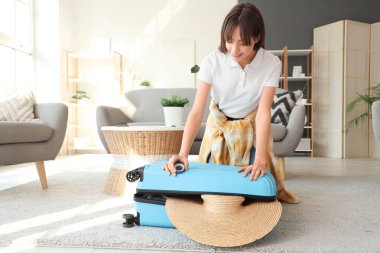 Evde pusula valizli bir kadın turist.