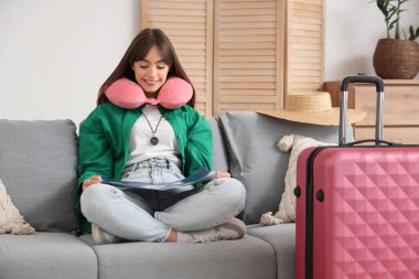 Pusula ve haritayla evdeki kanepede oturan kadın turist.