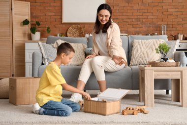 Anne ve oğlu evde hasır sepete oyuncak koyuyorlar.