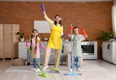 Anne ve çocukları kulaklıkla evde temizlik yaparken eğleniyorlar.